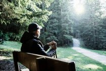 Senderista sentado en el banco mirando hacia otro lado, Madonna di Pietralba, Trentino-Alto Adige, Italia, Europa - foto de stock