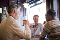 Tre uomini maturi, seduti insieme al pub, a parlare — Foto stock