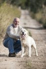 Retrato de homem sênior agachado ao lado do cão de estimação — Fotografia de Stock