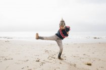 Jeune garçon équilibrage sur une jambe sur la plage — Photo de stock