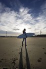 Молодая серфингистка стоит на пляже — стоковое фото