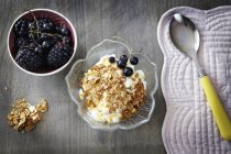 Greek yoghurt with honey and muesli and bowl of berries, overhead view — Stock Photo