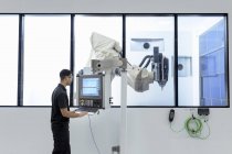 Ingeniero de robótica operando máquina de corte de robot en instalaciones de investigación de robótica - foto de stock
