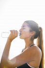 Jovem mulher bebendo água engarrafada durante o treinamento — Fotografia de Stock