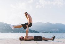 Deux jeunes hommes s'entraînent au bord de l'eau, Lac de Côme, Lombardie, Italie — Photo de stock