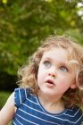 Портрет блондинки хвилястої волохатої дівчини з блакитними очима дивиться в парку — стокове фото