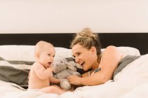 Donna a letto a giocare con la figlia del bambino — Foto stock