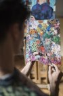 Вид через плечо на художника, смешивающего масляные краски на палитре — стоковое фото