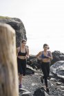 Две молодые женщины бегут по скалистому пляжу — стоковое фото
