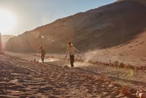 Boy and his brother pulling toy trucks along desert path, Atacama, Chile — Stock Photo