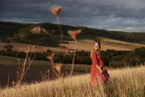 Portrait of happy pregnant woman in red dress on hillside — Stock Photo
