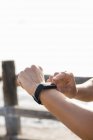 Молода жінка тренується на морській набережній дивиться на смарт-годинник, крупним планом руки — стокове фото