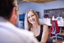 Blonde haired woman looking at colleague smiling — Stock Photo