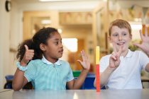 Schoolboy and girl counting on fingers in classroom at primary school — Stock Photo