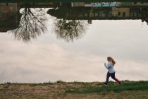 Викривлена молода жінка біжить на березі річки — стокове фото