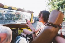 Jeune femme regardant smartphone dans un véhicule tout-terrain, Côme, Lombardie, Italie — Photo de stock