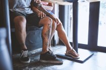 Waist down of multi ethnic hipster couple in cafe with hand on each others knee, Shanghai French Concession, Shanghai, China — Stock Photo