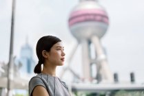 Junge Geschäftsfrau blickt weg auf Shanghai Finanzzentrum, China — Stockfoto