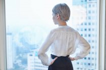 Rear view of businesswoman looking out of window — Stock Photo
