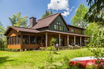 Casa di campagna in legno di abete rosso scuro e verde con veranda, Quebec, Canada — Foto stock