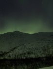 Aurora borealis over snow covered hills at night, Finnmark, Norway — Stock Photo