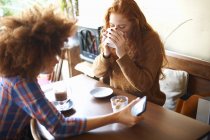 Двоє друзів зі смартфоном розслабляються в кафе — стокове фото