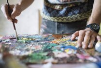 Künstler mischt Ölfarben auf Palette im Atelier — Stockfoto