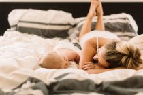 Baby girl lying on bed face to face with mother — Stock Photo