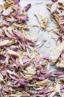 Draufsicht auf rosa getrocknete Blütenblätter auf grauer Oberfläche — Stockfoto