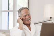 Homme en peignoir faisant un appel téléphonique, souriant — Photo de stock