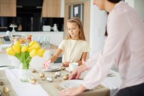 Mädchen und Mutter bereiten Tischdekoration am Ostertisch vor — Stockfoto