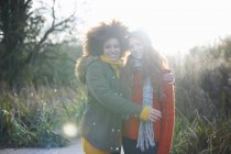 Female friends hugging and smiling at camera — Stock Photo