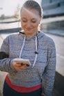 Curvaceous young woman training and looking at smartphone — Stock Photo
