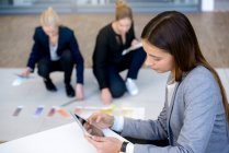 Junge Geschäftsfrau im Büro schaut auf digitales Tablet — Stockfoto