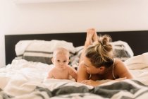 Porträt eines kleinen Mädchens, das mit seiner Mutter im Bett liegt — Stockfoto