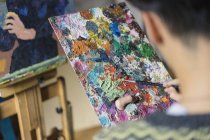 Männlicher Künstler mischt Ölfarbe auf Palette im Künstleratelier — Stockfoto