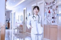 Portrait of doctor in hospital corridor looking at camera smiling — Stock Photo