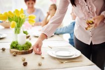 Donna e famiglia che preparano le ambientazioni del posto al tavolo da pranzo pasquale — Foto stock