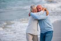 Casal abraçando e rindo à beira-mar — Fotografia de Stock