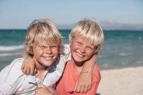 Portrait of smiling brothers, arms around each other, looking at camera — Stock Photo