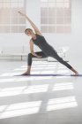 Donna a casa facendo yoga su tappetino yoga — Foto stock