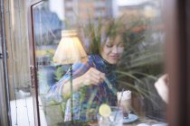 Blick durch das Fenster einer Frau in einem Café, die heiße Schokolade genießt — Stockfoto
