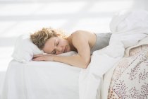 Frau schläft zu Hause im weißen Bett — Stockfoto