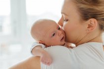 Junge Frau küsst Baby-Tochter auf Wange — Stockfoto