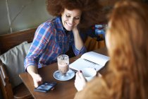 Amici di sesso femminile con smartphone rilassante nel caffè — Foto stock