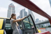 Young businesswoman beside yellow cab at Shanghai financial center, China — Stock Photo