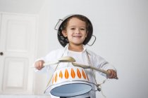 Boy drumming on saucepan and smiling at camera — Stock Photo