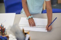 Школярка, використовуючи лінійку, щоб малювати в класі столу в початковій школі, обрізаний — стокове фото