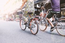 Талія вниз подання multi етнічних hipster пари велосипеді уздовж вулиці, Шанхай Французької концесії, Шанхай, Китай — стокове фото
