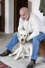 Retrato de hombre mayor en casa con perro de compañía - foto de stock